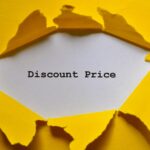 Torn yellow paper reveals a white card that reads “Discount Price.”